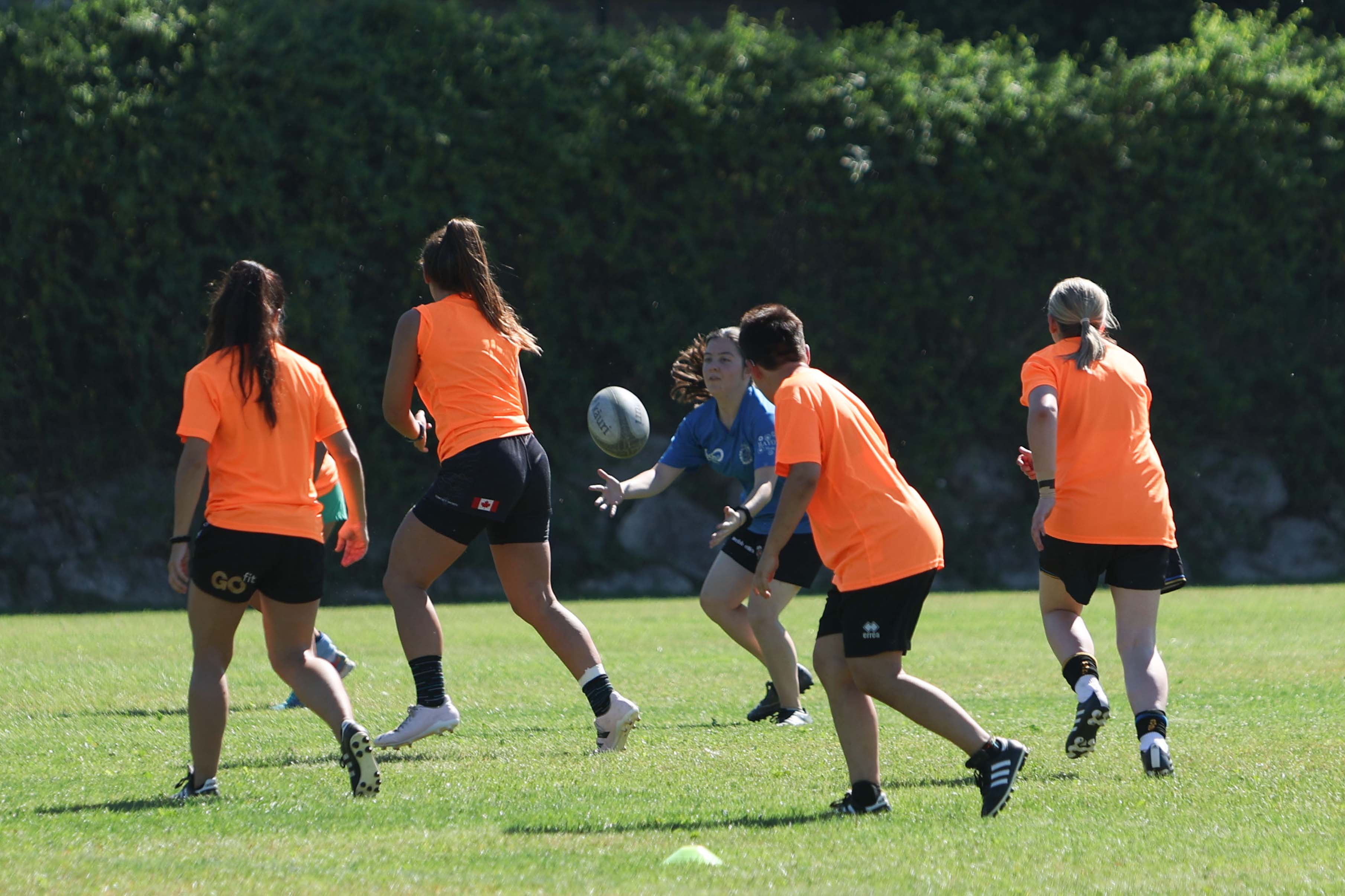 Jugadoras se pasan la pelota durante un partido de rugby inclusivo. 